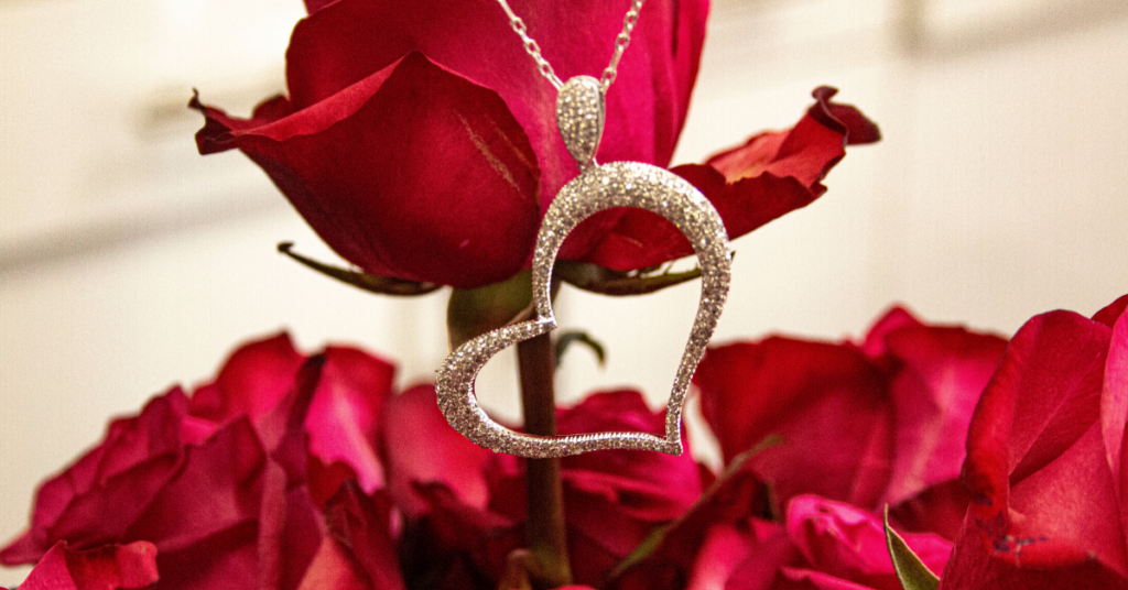 Pave diamond heart pendant and a vase of red roses