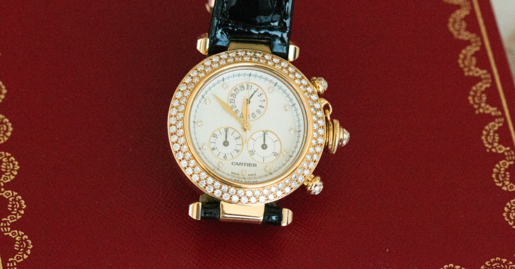 Cartier pasha gold and diamond watch with a black leather strap.