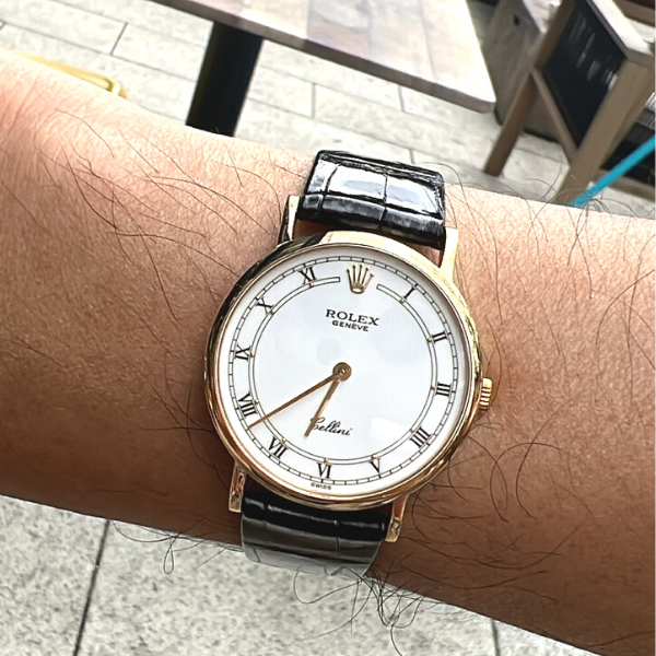 Rolex Cellini in 18K yellow gold with a white dial and black leather strap.